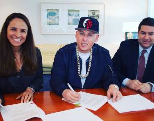 Cosculluela (centro) firmando el acuerdo con Warner Music Latin (Foto tomada de su Facebook Oficial)